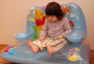 Books & TV for the long nights, by Charles Harris - photo: small girl reading a picture book - Moonsun1981, Attribution, via Wikimedia Commons